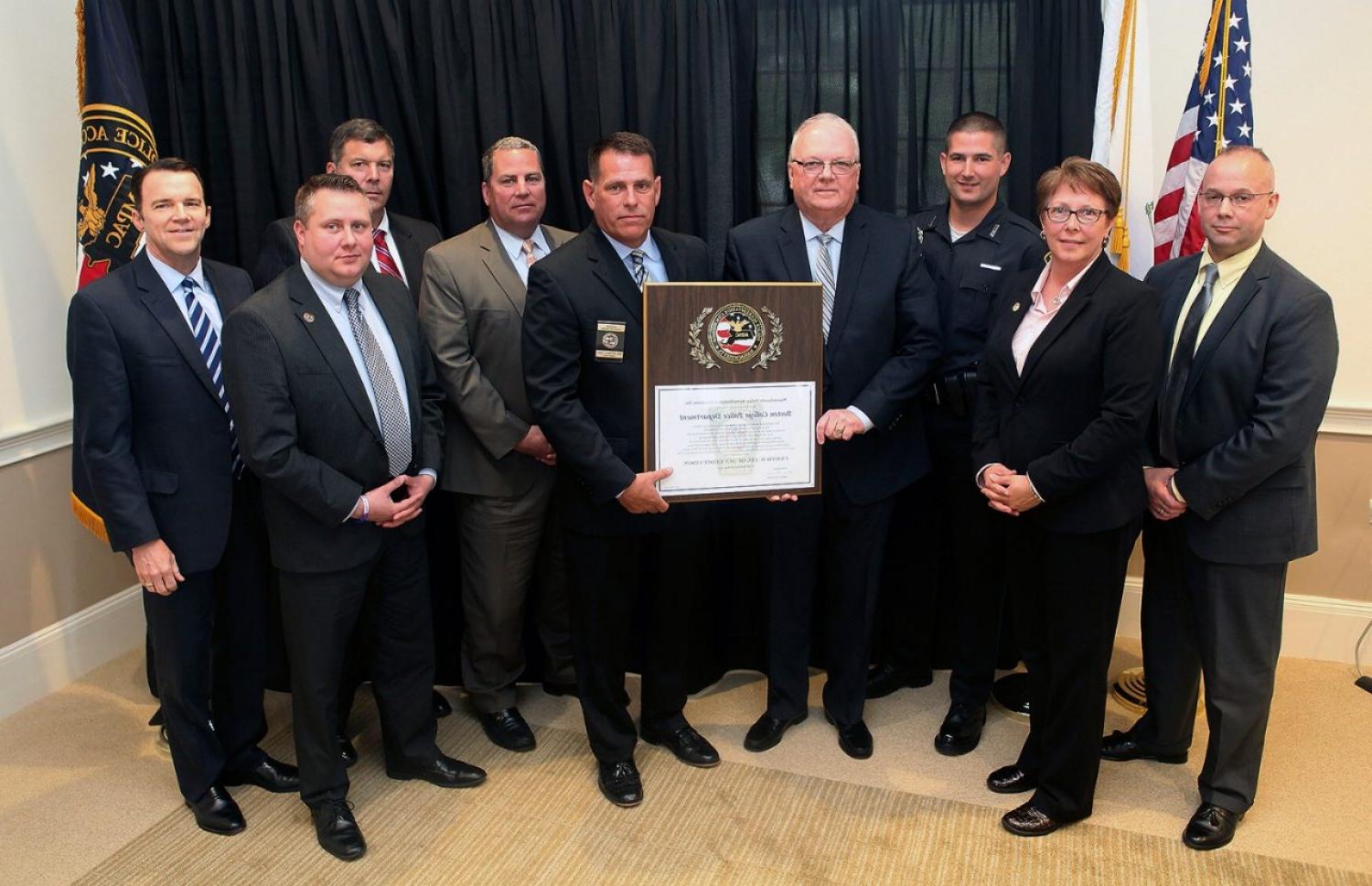 Boston College Executive Director of Public Safety and Police Chief John King, fourth from left, at a ceremony marking BC Police Department's reaccreditaiton. From left, Massachusetts Police Accreditation Commission Vice President Russ Stevens; BCPD Lieutenant and Accreditation Manager Laurene Spiess; BCPD Officer and Accreditation Assessor Robert Wayne; MPAC President Matt Clancy; BC Associate Director of Public Safety and Deputy Chief Tom Atkinson; BC Detective Lieutenant David Flaherty; BCPD Operations Lieutenant Jeff Postell, and BC Financial Vice President and Treasurer John Burke.